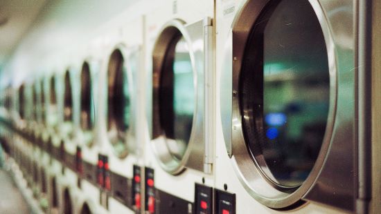 Many washing machines stacked next to each other inside a room