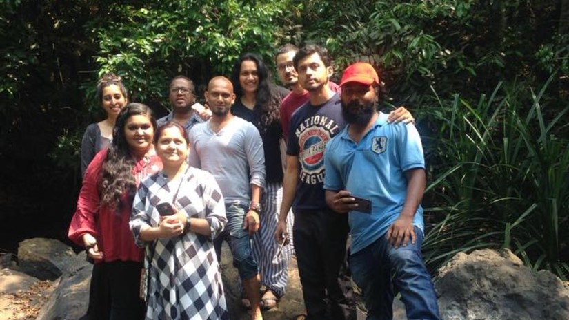 Group of people standing together on rocks in a natural setting, smiling at the camera.