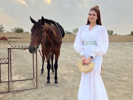 a woman standing by a Horse at inflated trampoline surrounded by trees at Themis Mudhouse - A Nature's Retreat Resort & Wellness