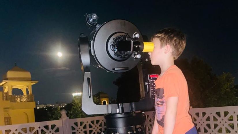 a child glancing out of a large telescope