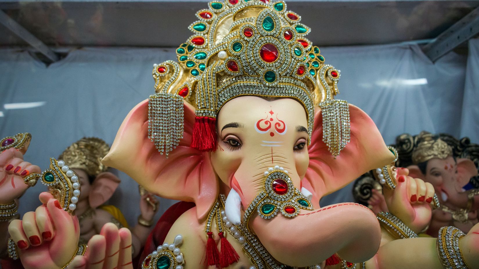 an idol of lord ganesha with a golden crown decorated with blue and red stones