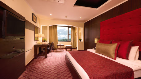 Renest Hotel Manali - Interior view of the canary room with a king size bed in red and brown decor