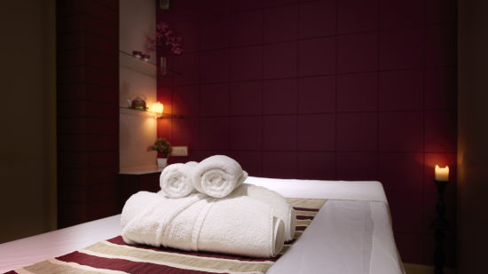 Renest Hotel Manali - Interior view of the spa featuring a bed, red wall and white towels stacked on one another 