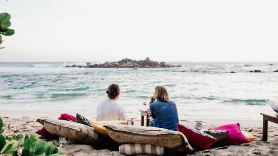 people resting on cushions at beach