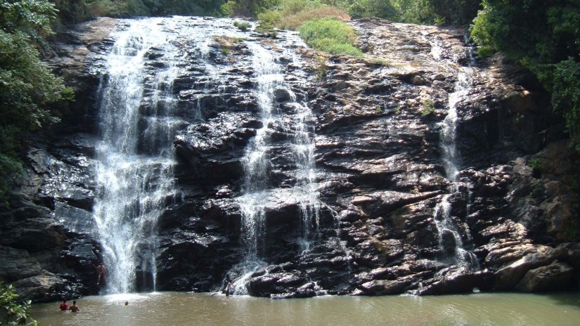 Water Falls iA scenic waterfall surrounded by trees with a pool below where people are swimming.n Coorg, Amanvana Resort Spa, Places To Visit In Coorg 1