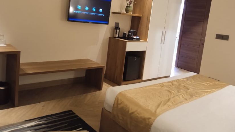 side angle view of bedroom with a king size bed and room amenities like a flat-screen television, an electric kettle and much more