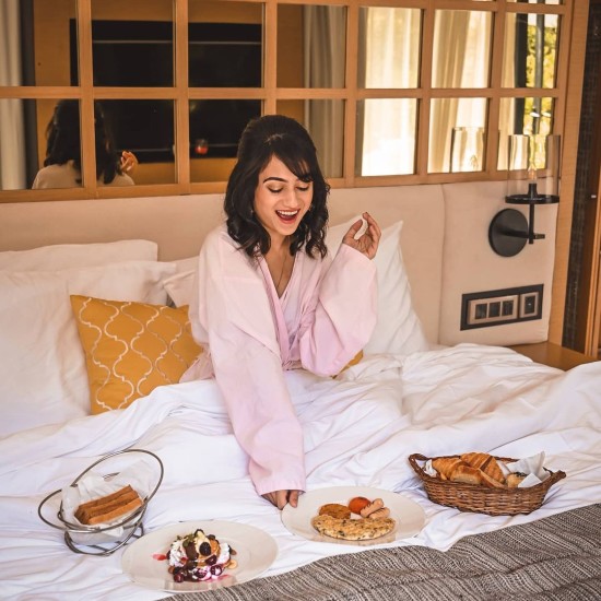 Lady wearing pink robes delighted at the breakfast in bed choices