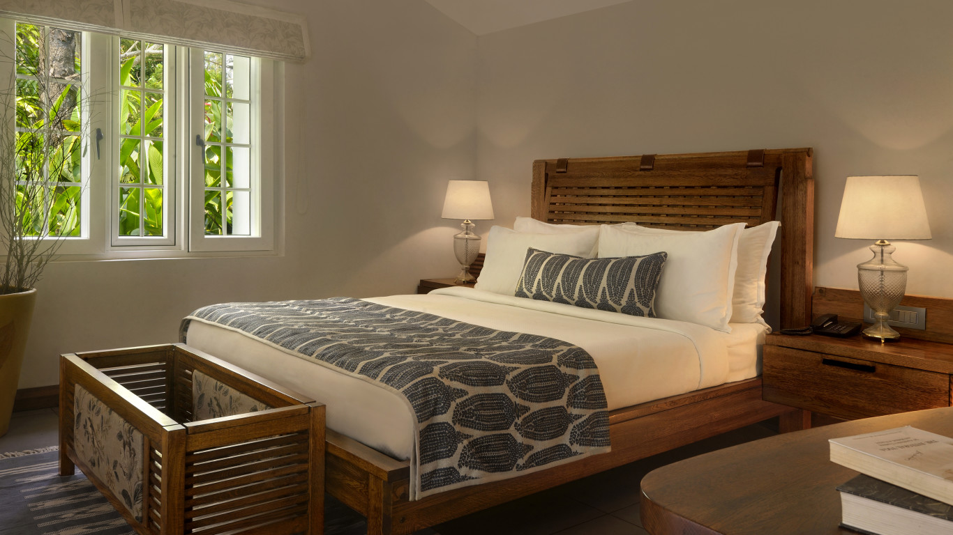 Elegant bedroom with a large bed, two lamps, and a window with greenery outside.