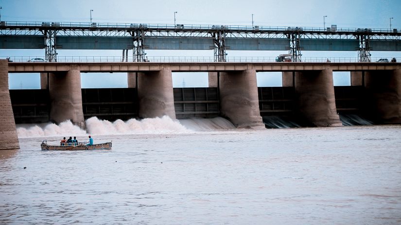 Water flowing from a dam with a boat sailing in the river below