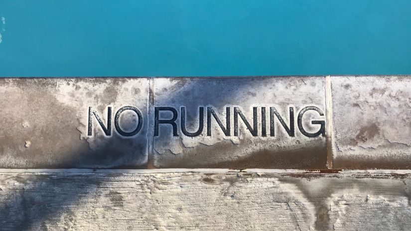 a stone slab with No Running carved in to it next to a swimming pool