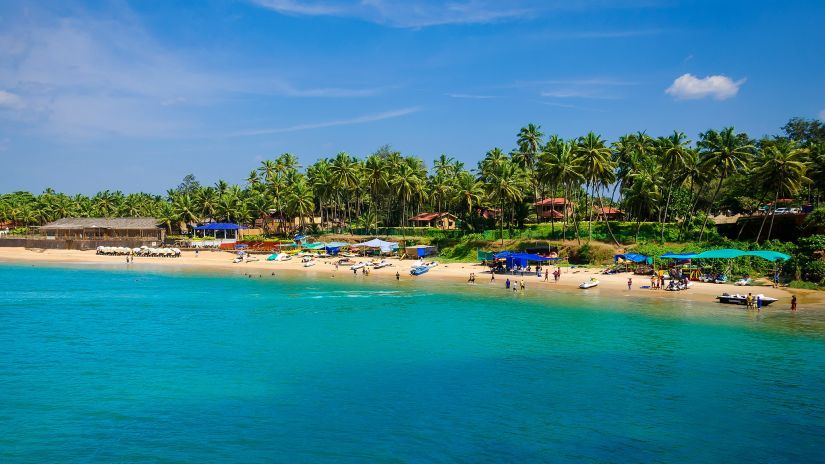 people basking in the sun near the blue water of the Colva Beach