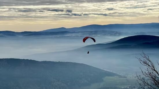 a person paragliding amid the cloud covered mountains