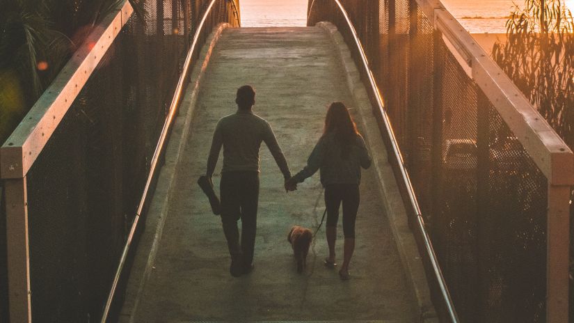 couple holding hands, walking across a bridge