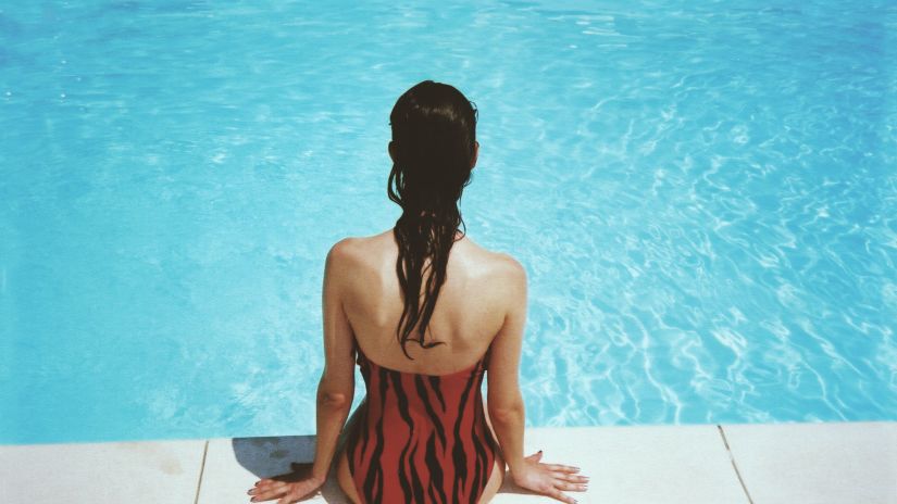 A girl sitting on the side of the swimming pool