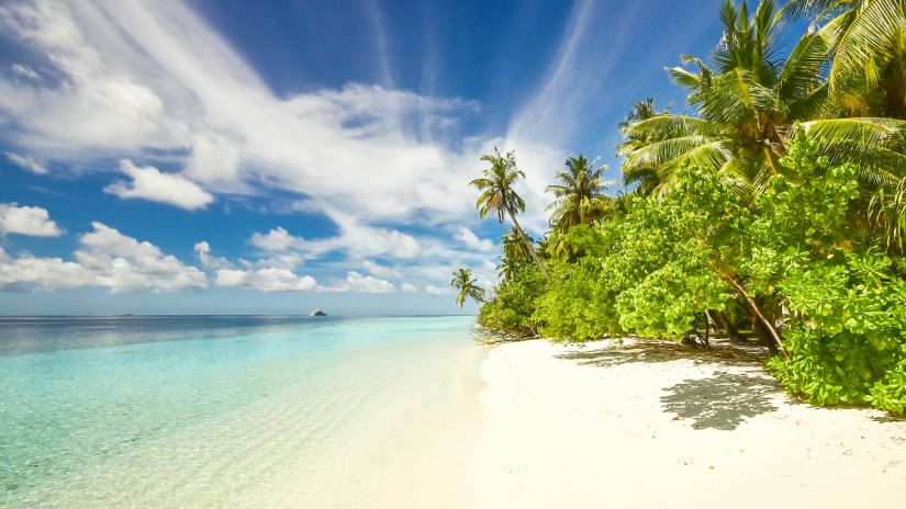 Beach with white sand and clear, blue water on a cloudy day