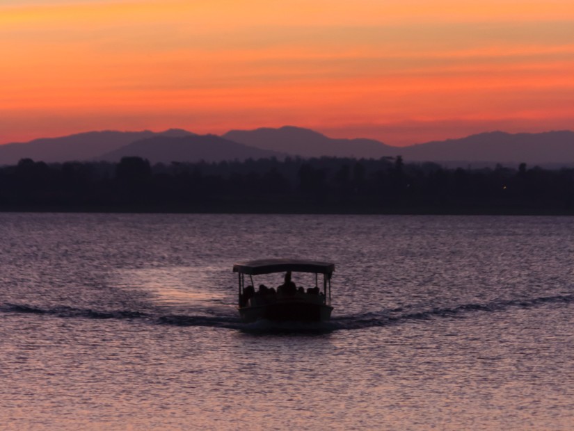 a view of sunset with a boat sailing on the river