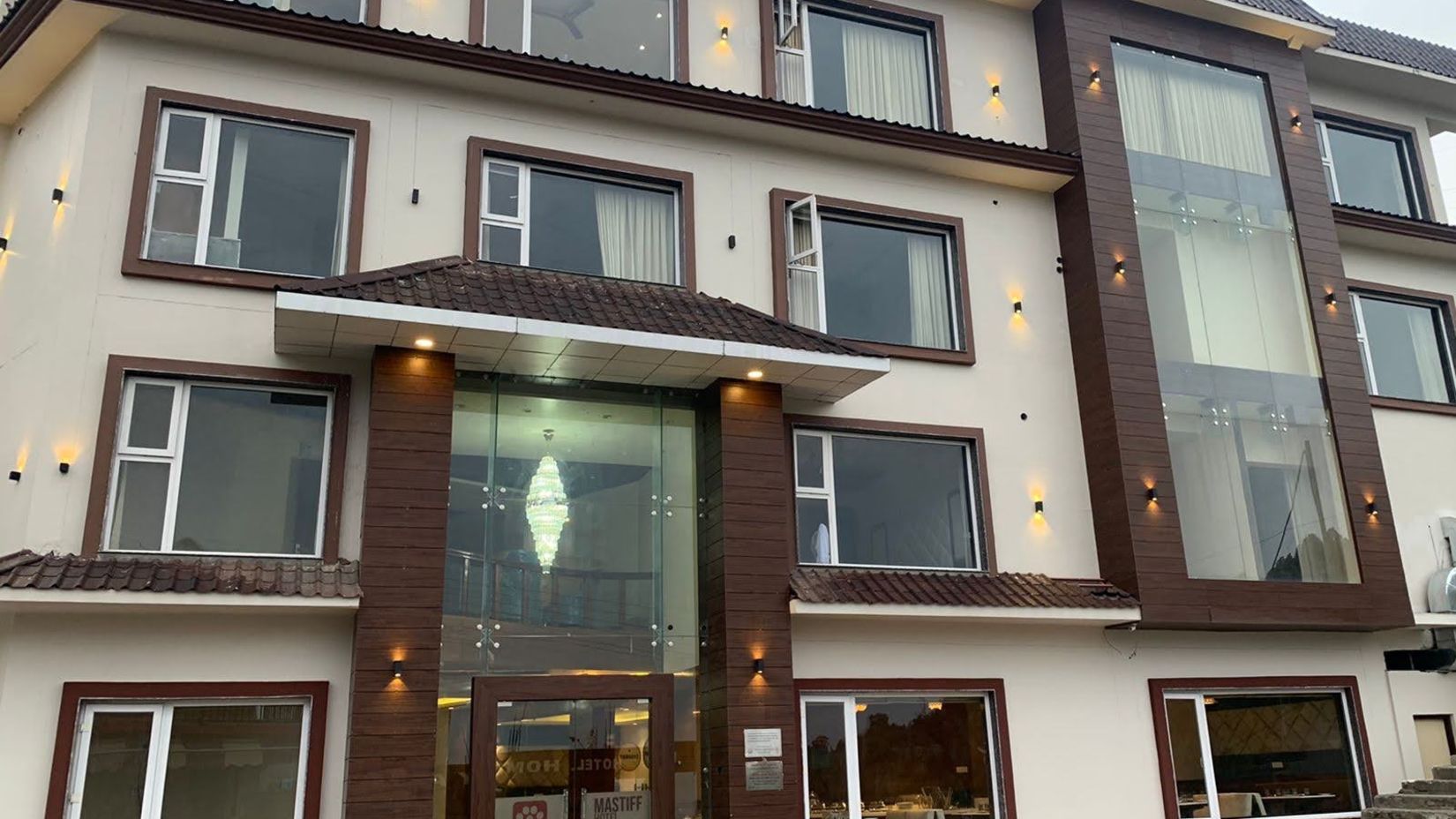 exterior of a hotel building that is shot from a lower angle during the day with a multicolour carpet on the floor near the entrance - 