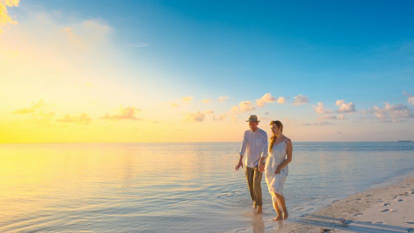 A couple walking alongside the beach holding hands