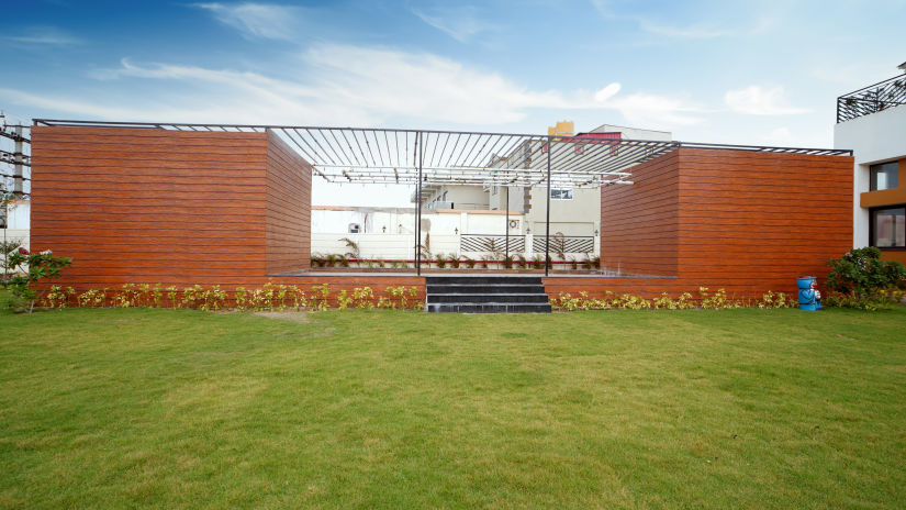 a massive grass area with a building in the background that has open brick walls - Shanti Seaview Resort & Spa