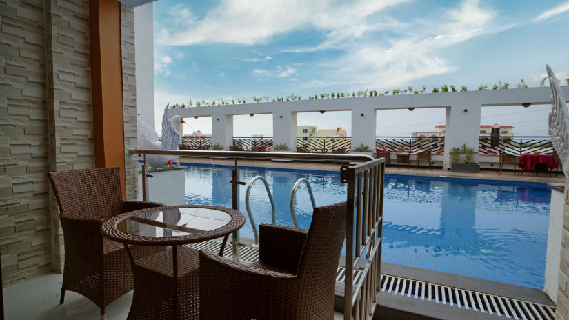 Seats in a balcony with a small table with views of the swimming pool inside one of the rooms - Shanti Seaview Resort & Spa