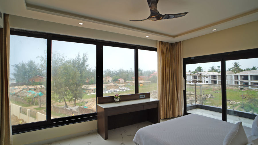 a double bed with a table opposite it and floor to ceiling windows covering the room - Shanti Seaview Resort & Spa