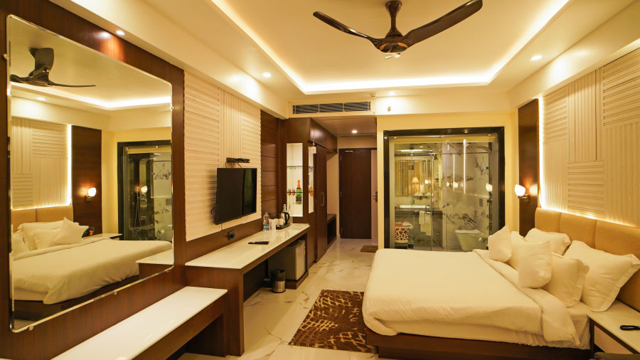 a double bed with a tv opposite to it wall mounted and a ceiling fan inside one of the rooms - Shanti Seaview Resort & Spa