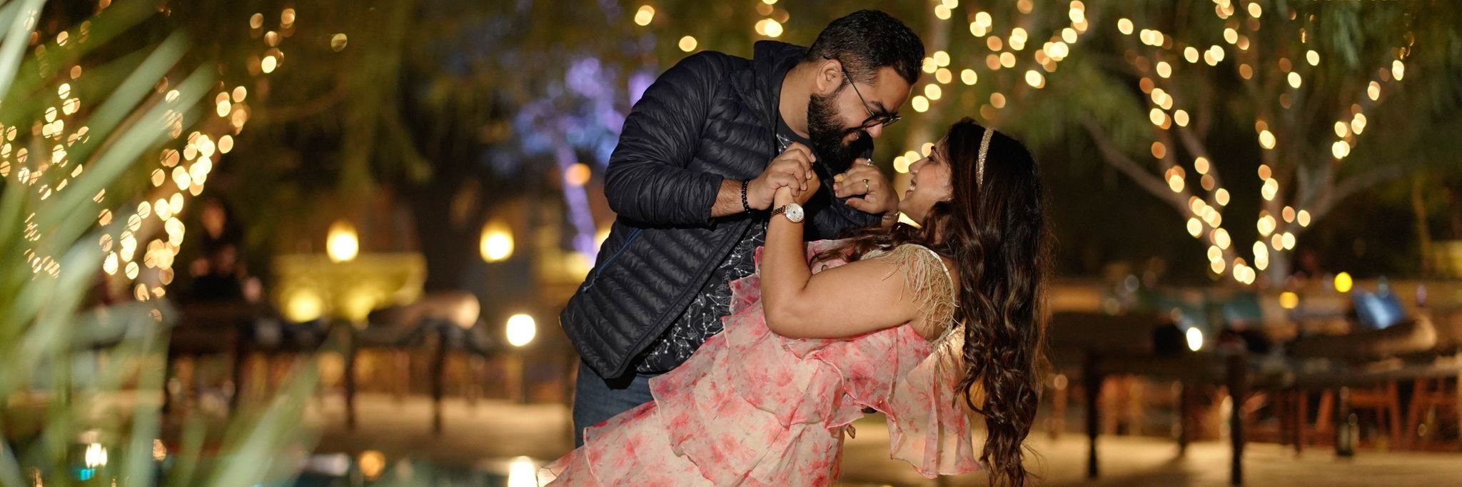 a couple posing in a dancing position with decorations in the background