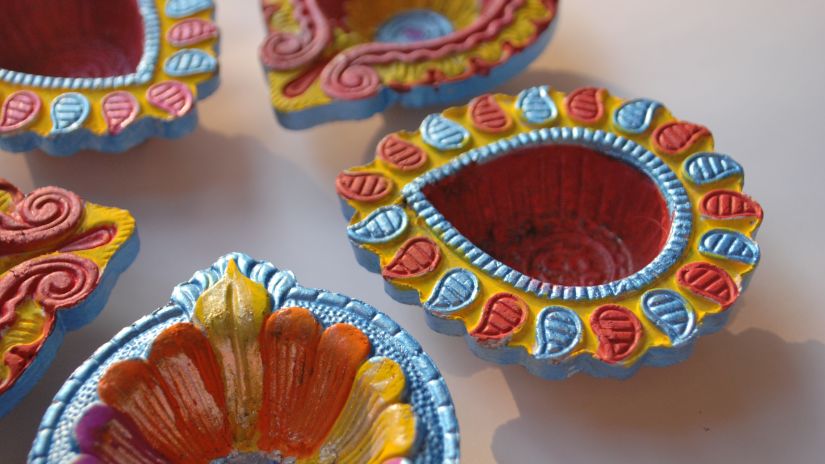 five multi-colored diyas placed together