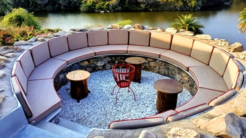 a round sofa with three small tables in front of it and the lake and forest in the background - Chunda Shikar Oudi, udaipur