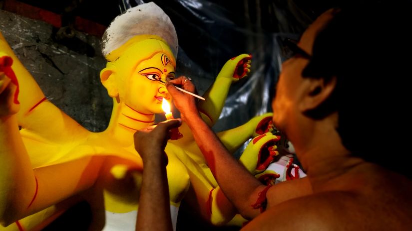 an image of a craftsman delicately painting the idol of devi durga