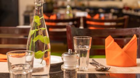 Glass  bottle and glasses along with an orange napkin at Kyriad Prestige Calangute, Goa