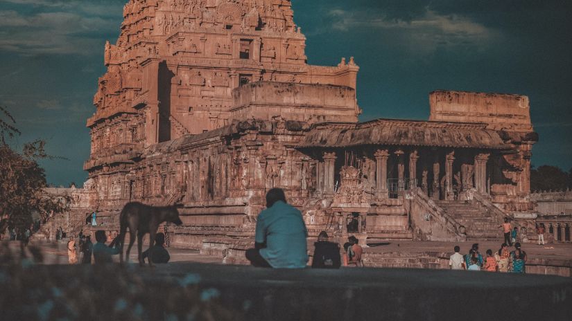 A hindu temple with intricate architecture outside on the roof as seen from a distance