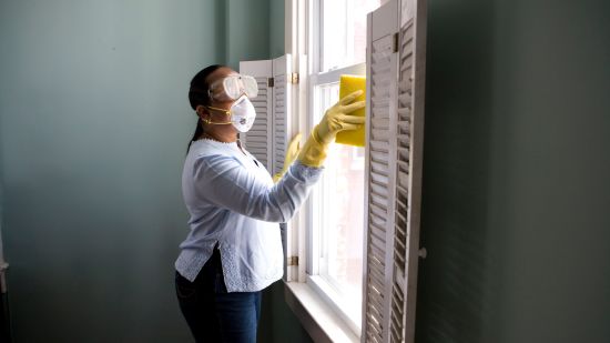 an image of a woman cleaning windows with a yellow cloth as a part of daily housekeeping