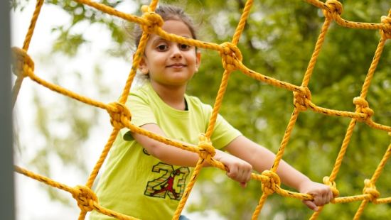 Kid on a commando net ride at inflated trampoline surrounded by trees at Themis Mudhouse - A Nature's Retreat Resort & Wellness