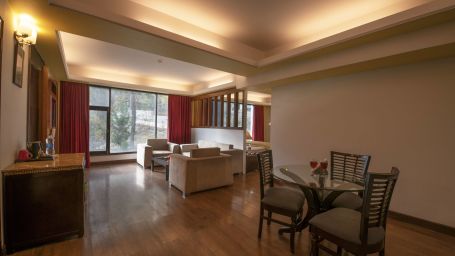 A living room with a dining table and chairs, sofas, and a wall painting - Mastiff Grand, Manali