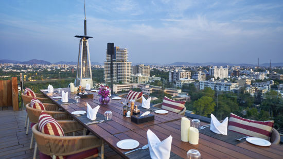 alt-text Seating arrangement in a rooftop with a view of the city's skyline - Parallel Hotel, Udaipur