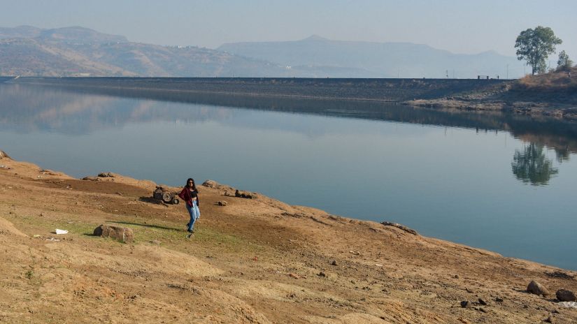 A girl posing in front of Pawna Lake with mountains in the background