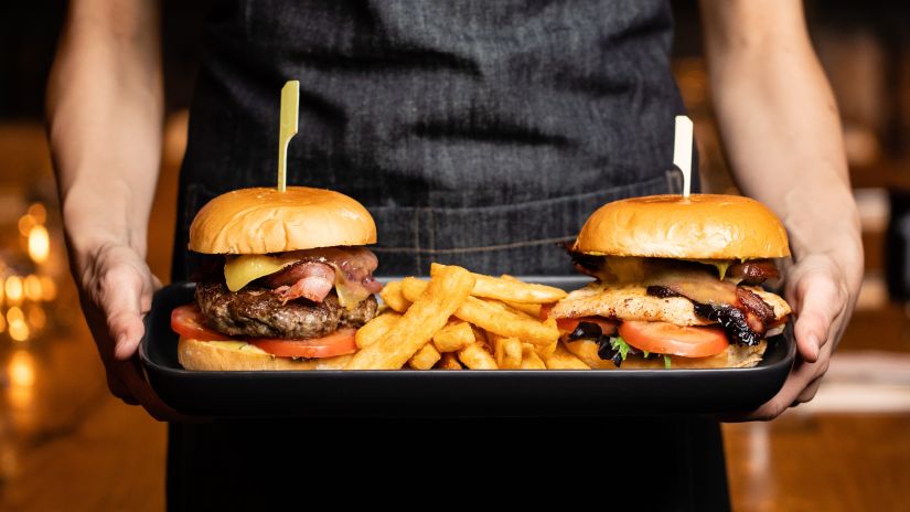 A waiter bringing a tray of two burgers