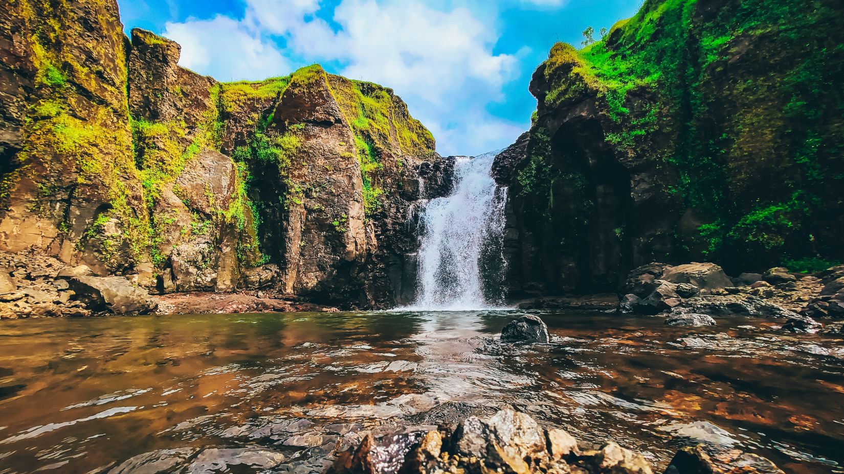 view of a waterfall amidst hills