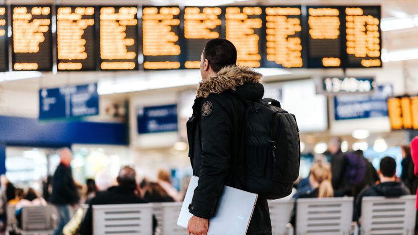 IMage of a man carrying a laptop and a backpack while standing inside an airport