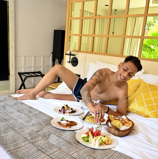 Guy wearing shorts enjoying breakfast in bed at our 5-star hotel in South Goa