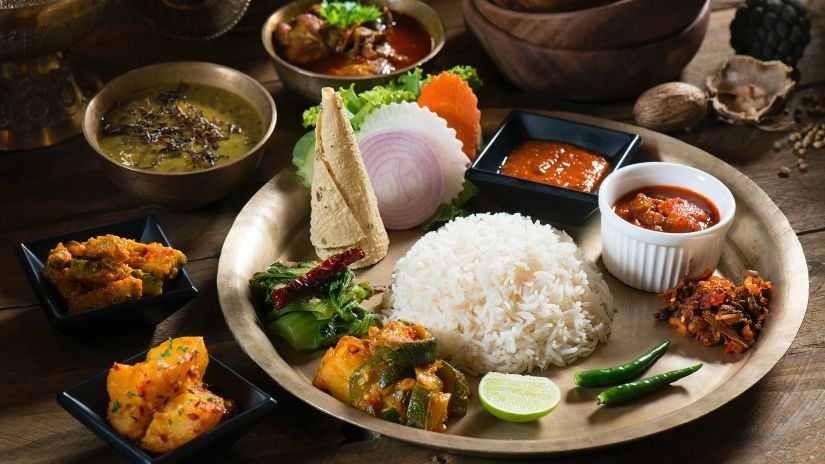 an authentic nepali thali with rice dal papad curries garnished with lemon and chilli
