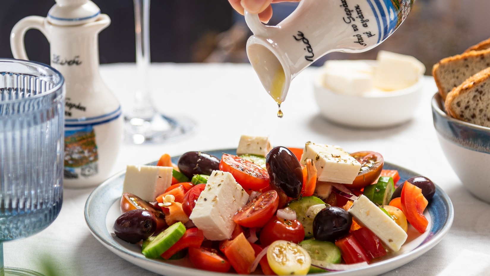 A person pouring dressing on a salad