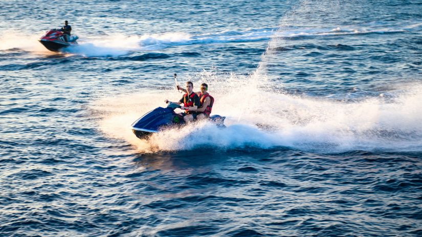 two jet skis in view going being ridden by people travelling on a waterbody