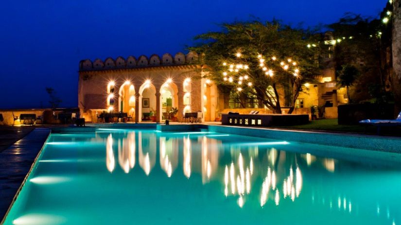 A vibrant blue pool with the resort at the background - Hill Fort Kesroli Alwar Rajasthan