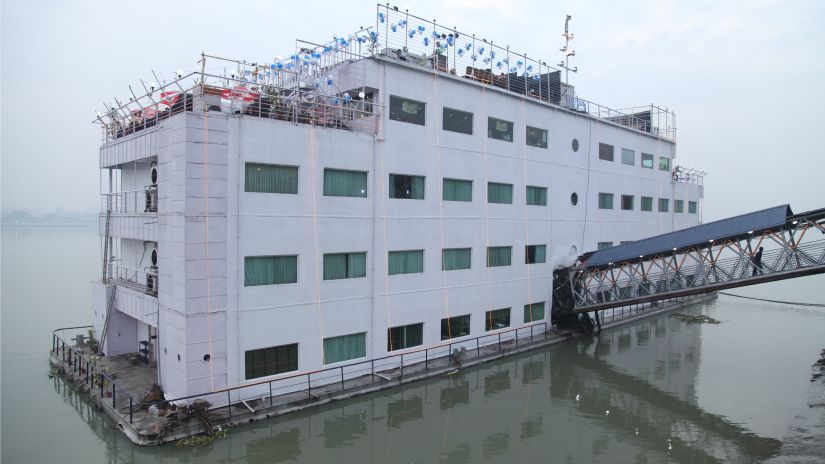 A floating structure on the water, under construction, with scaffolding and blue canopies on top. - Polo Floatel, Kolkata