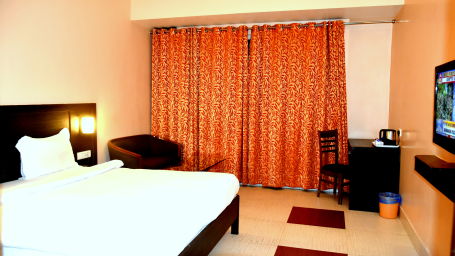 A sideview of Executive Room with bed, TV and a desk | Hotel City Inn, Varanasi