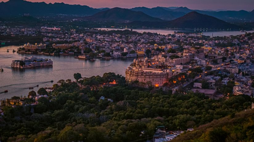 As dusk approaches, Udaipur's palaces and lakes are bathed in a warm glow that creates a silhouette of the city against the Aravalli Hills