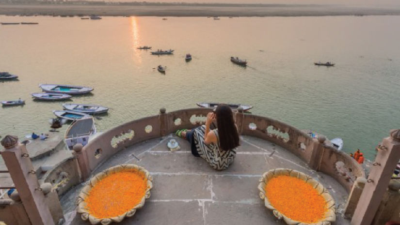 Brij Hotels - person sitting on a balcony enjoying the sun setting over a lake