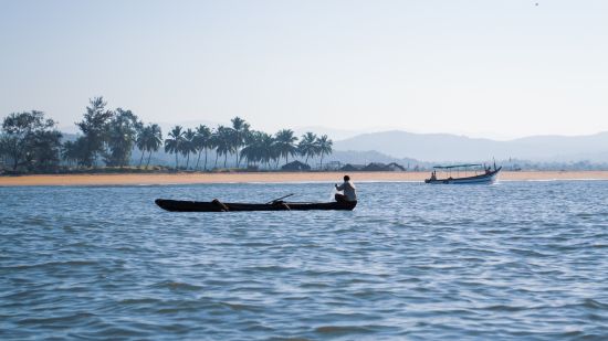 fishing boats in the arabian sea on palolem beach with land in the background